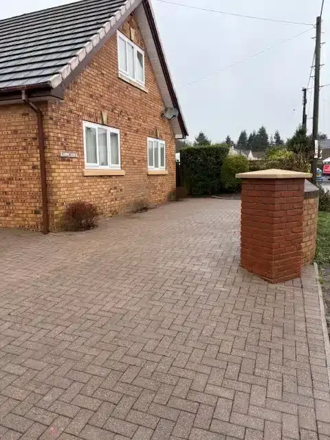 Clean driveway beside a brick house.